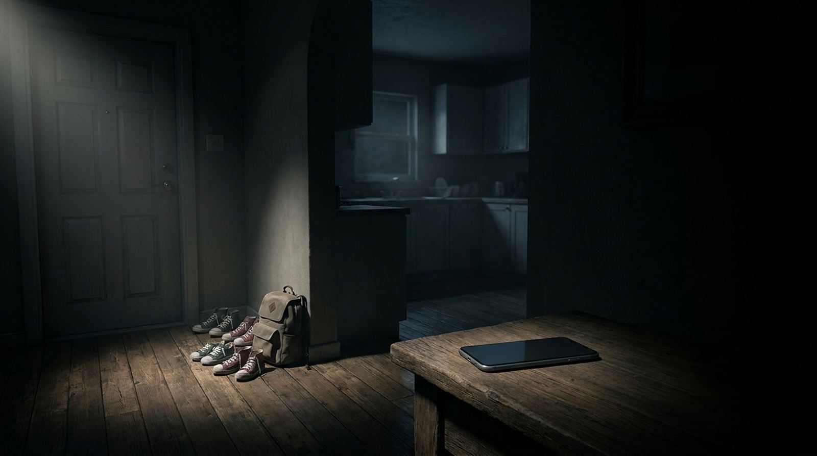 Children's sneakers and a backpack by a dark front door, a phone on a table and an empty kitchen beyond